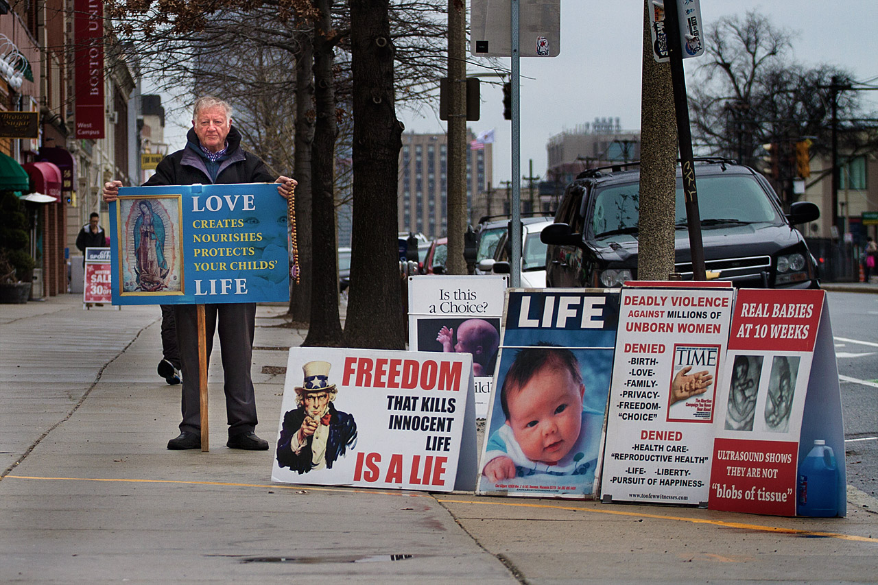 Protester Frank Porter stands amid anti-abortion signs just beyond the 35-foot perimeter outside of a Planned Parenthood office on Commonwealth Avenue in Boston. (Jesse Costa/WBUR)