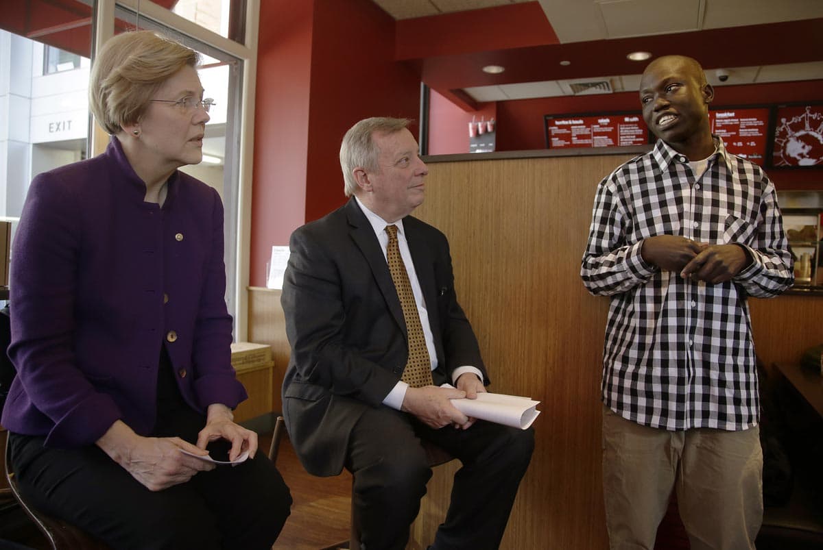 Sen. Elizabeth Warren and Senate Majority Whip Richard Durbin, of Ill., listen as Emmanuel Sebit, an immigrant from South Sudan and a baggage handler at Logan Airport, speaks during a minimum wage roundtable discussion at a Boloco in Boston in February. (Stephan Savoia/AP)