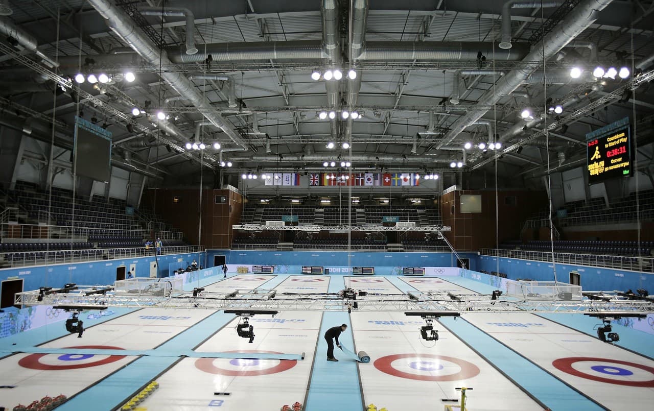 A broadcast camera crew member lays out carpets on ice sheets while making preparations to adjust television cameras at the Ice Cube Curling Center ahead of the 2014 Winter Olympics, Tuesday, Feb. 4, 2014, in Sochi, Russia. (Wong Maye-E/AP)