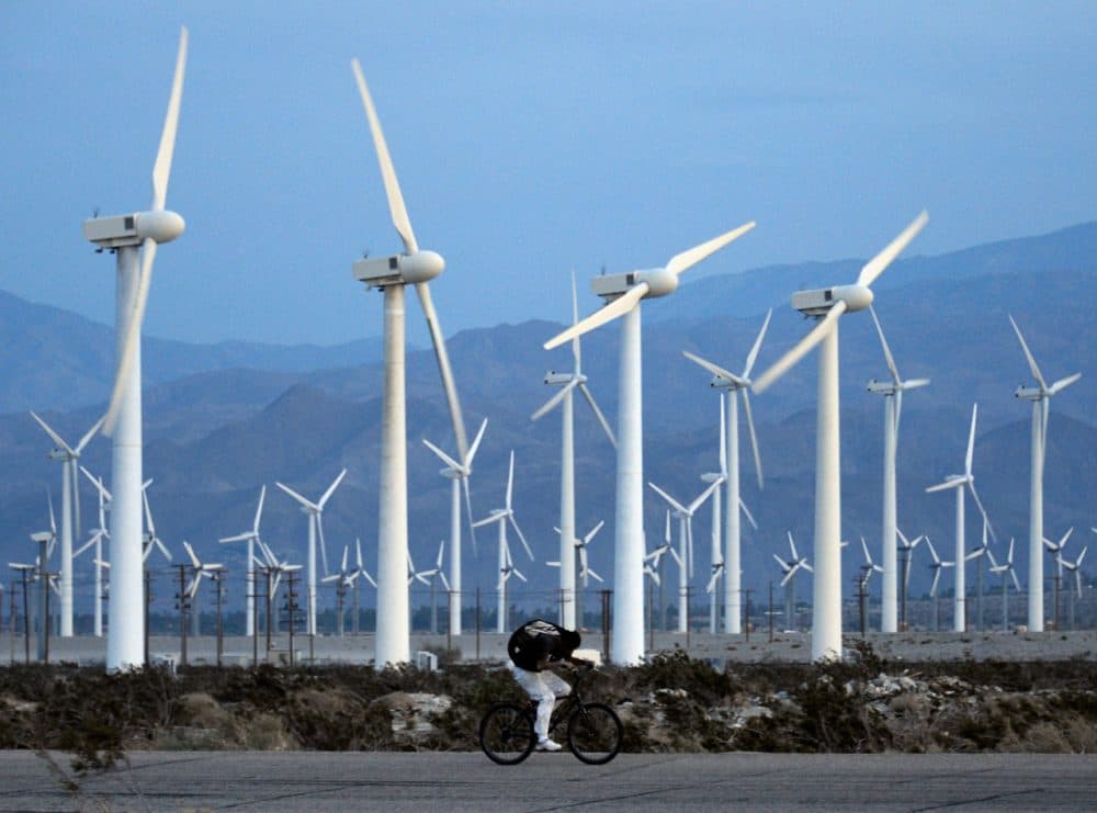 A man rids his bike against the win as giant wind turbines are powered by strong winds at sunset on March 27, 2013 in Palm Springs, California. (Kevork Djansezian/Getty Images)