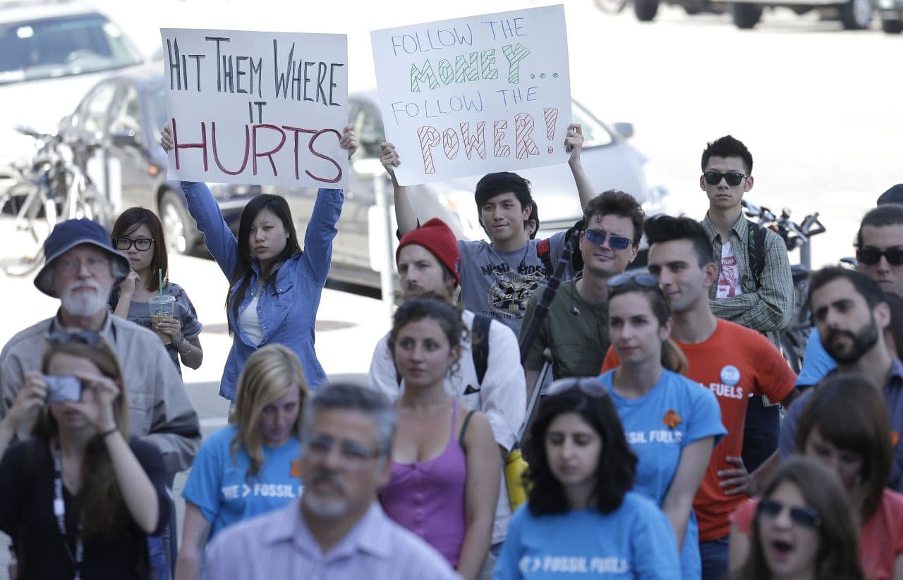 College students and supporters hold up signs at a rally to support fossil fuel divestment outside of City Hall in San Francisco on May 2, 2013. In an effort to slow the pace of climate change, students at more than 400 colleges are asking their schools to stop investing in fossil fuel companies.