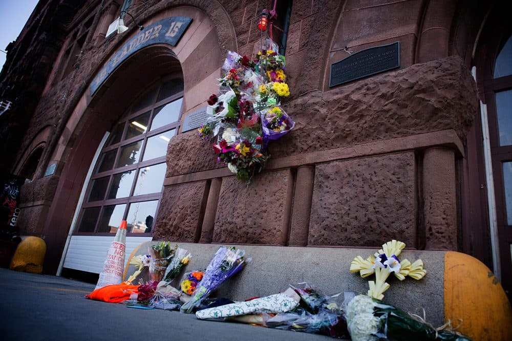 A makeshift memorial at Engine 33 fire station on Boylston Street is pictured Thursday. Engine 33 was the station of fallen firefighters Edward Walsh and Michael Kennedy. (Jesse Costa/WBUR)
