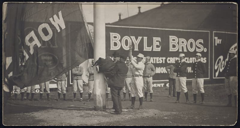Jimmy Collins of the Boston Americans raises the first championship flag on opening day of 1904, in celebration of winning the first World Series. Cy Young is fourth from right. (Boston Public Library) 