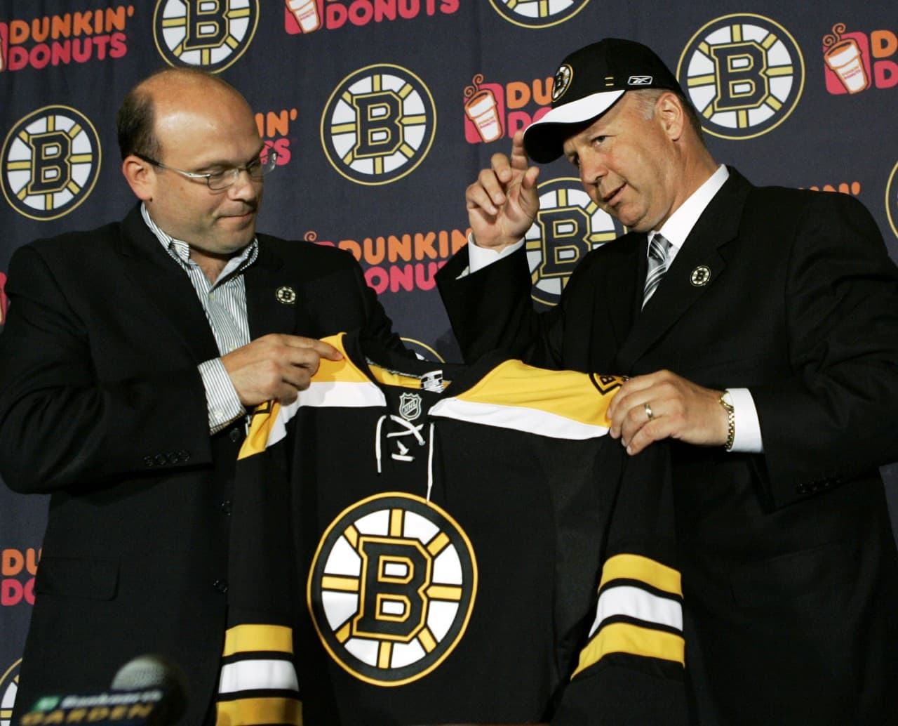 Boston Bruins hockey head coach Claude Julien, right, puts a team cap on and holds a jersey with Bruins General Manager Peter Chiarelli at a news conference in Boston Thursday, June 21, 2007. (Elise Amendola/AP)
