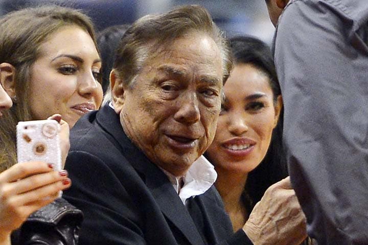 In this photo taken on Friday, Oct. 25, 2013, Los Angeles Clippers owner Donald Sterling, center, and V. Stiviano, right, watch the Clippers play the Sacramento Kings during the first half of an NBA basketball game, in Los Angeles. The NBA is investigating a report of an audio recording in which a man purported to be Sterling makes racist remarks while speaking to his Stiviano. (AP)