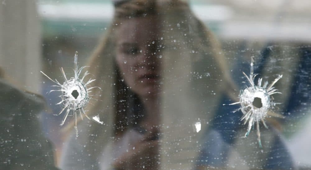 A woman looks at the bullet holes on the window of IV Deli Mark where Friday night's mass shooting took place by a drive-by shooter on Saturday, May 24, 2014, in Isla Vista, Calif. (Jae C. Hong/AP)