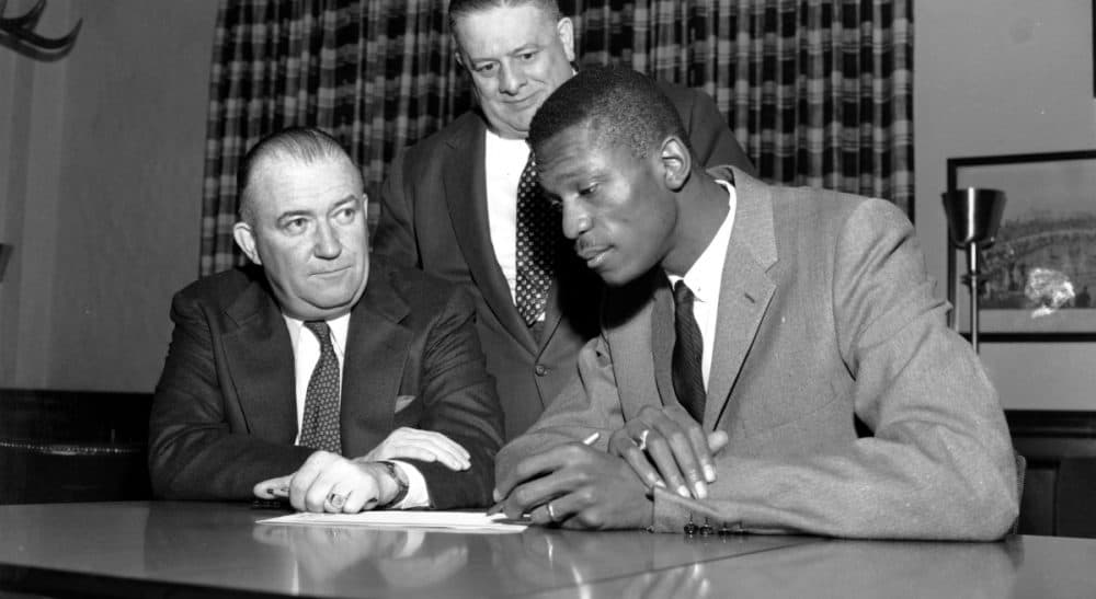 Bill Russell signs the contract with the Boston Celtics in 1956. Seated at his left is Celtics co-owner and president Walter Brown, and standing behind him is co-owner Lou Pieri. (AP)