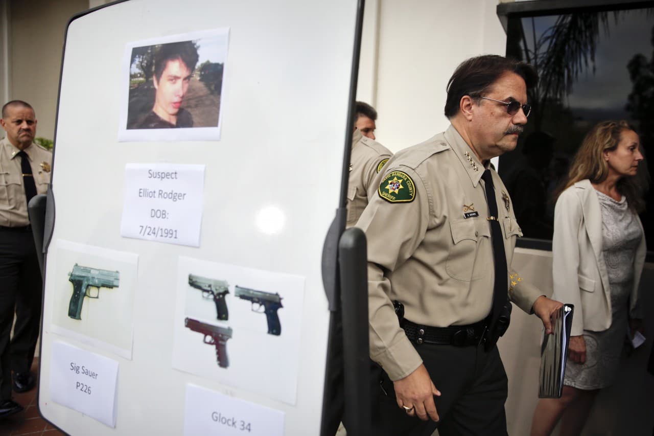 Santa Barbara County Sheriff Bill Brown, right, walks past a board showing the photos of suspected gunman Elliot Rodger and the weapons he used in Friday night's mass shooting that took place in Isla Vista, Calif., after a news conference on Saturday, May 24, 2014, in Santa Barbara, Calif. (Jae C. Hong/AP)