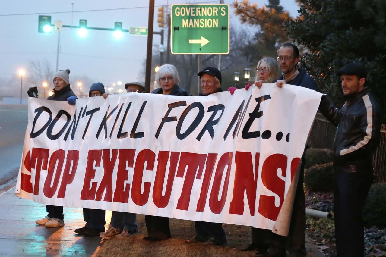 Bundled up against the cold, death penalty opponents hold a sign outside the Governor's mansion in Oklahoma City, Thursday, Jan. 9, 2014, protesting the McAlester, Okla., execution of Michael Lee Wilson. A recently botched execution of another Oklahoma prisoner has prompted further debate around the use of unknown chemicals to kill convicted criminals. (AP) 