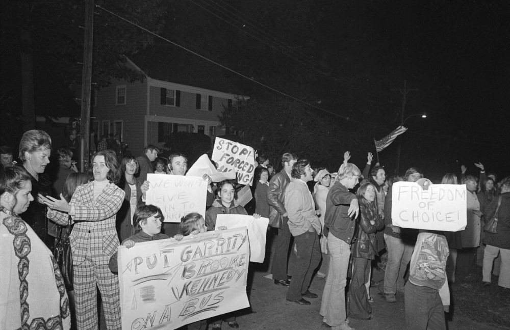 Demonstrators carrying signs gather the night of Oct. 5, 1974 outside the home of U.S. District Judge W. Arthur Garrity protesting the forced busing of Boston&#8217;s schoolchildren. 
