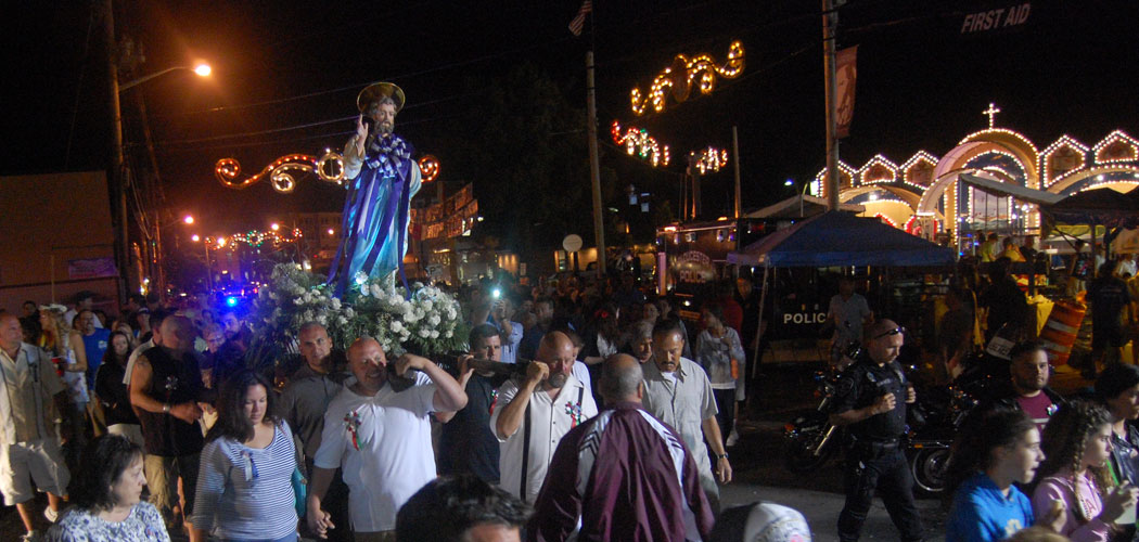Men carry the St. Peter statue past the Fiesta’s carnival and altar during the closing procession Sunday night. (Greg Cook)