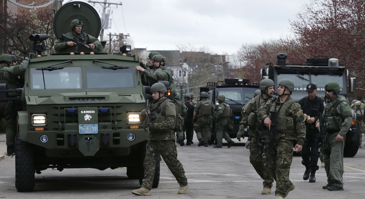 Carol Rose and Kade Crockford: "A thick blue wall of police silence is obstructing the public’s access to timely and accurate data about SWAT deployments." Pictured: A SWAT team unloads from their armored vehicles as they go door to door while searching for a suspect in the Boston Marathon bombings in Watertown, Mass., Friday, April 19, 2013. (Charles Krupa/AP)