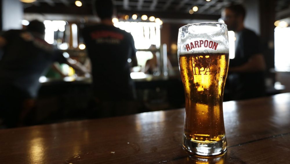 A glass of Rich and Dan's Rye IPA rests on the counter as bartenders pour drafts for patrons in the Beer Hall at the Harpoon Brewery in the Seaport District of Boston. (Charles Krupa/AP)