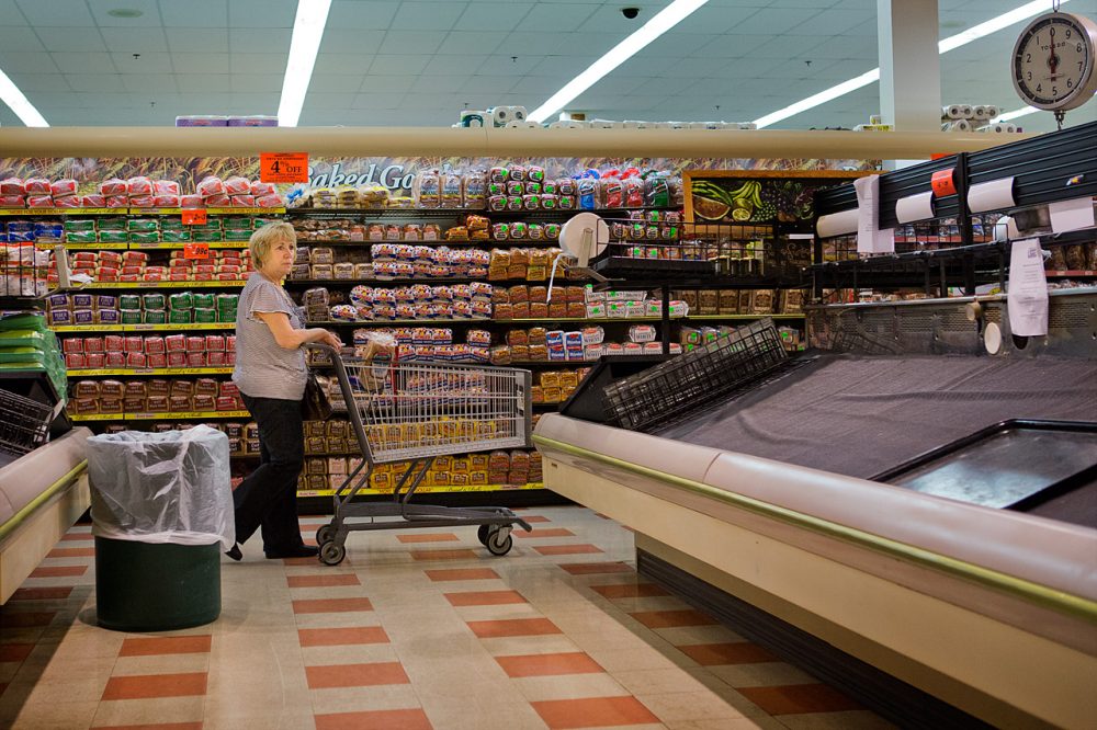 A customer walks past empty shelves at a Somerville Market Basket on July 22. The 40-day dispute is now over. (Jesse Costa/WBUR)