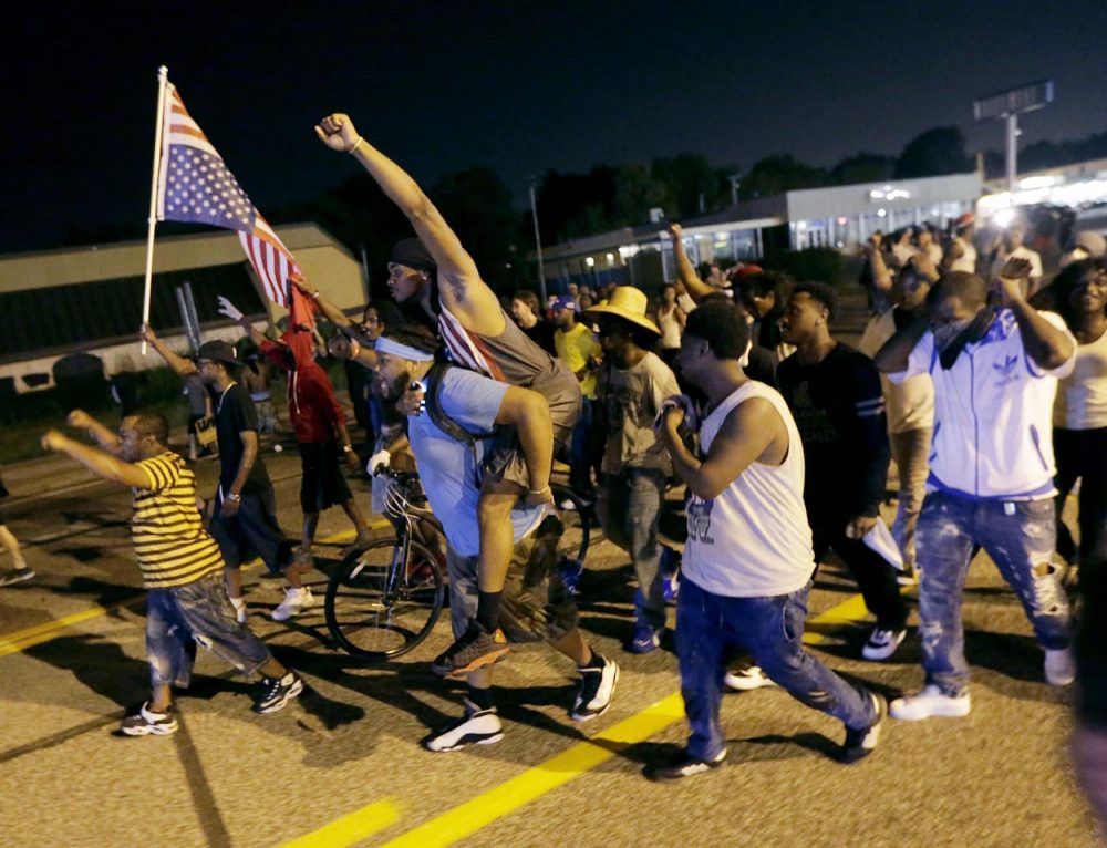 People march down the street after a standoff with police Monday in Ferguson. (Charlie Riedel/AP)