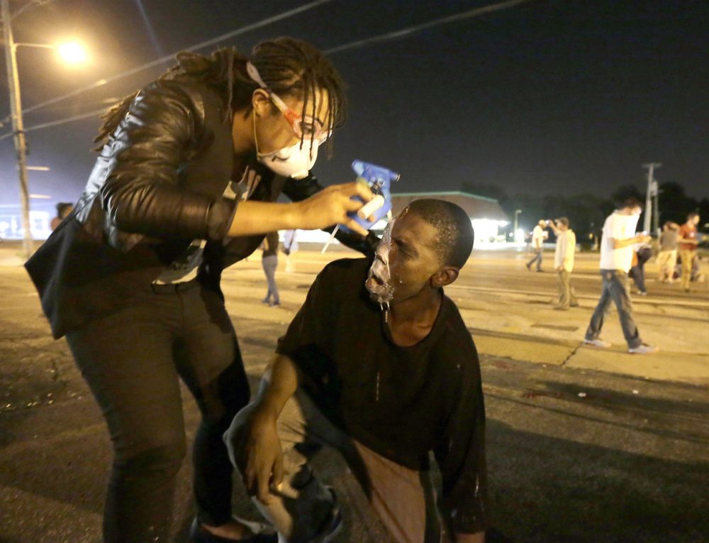 A man is helped ease the effects of tear gas during a protest Monday. (Charlie Riedel/AP)