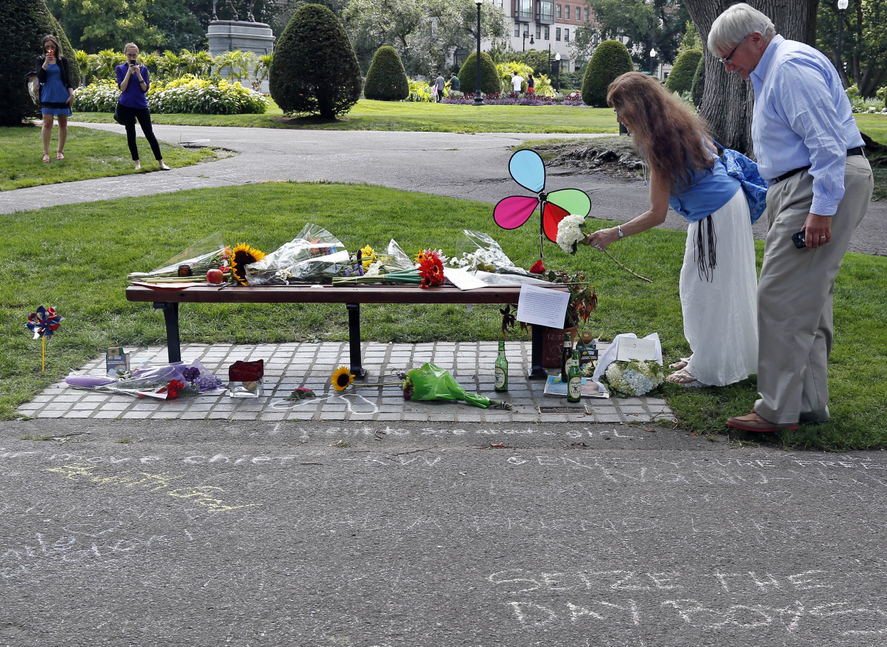 Don Makson watches as Suzette Demarais places flowers on a bench at Boston's Public Garden, Tuesday, Aug. 12, 2014, where a small memorial has sprung up at the place where Robin Williams filmed a scene during the movie, "Good Will Hunting." Williams, 63, died at his San Francisco Bay Area home Monday in an apparent suicide. (AP)