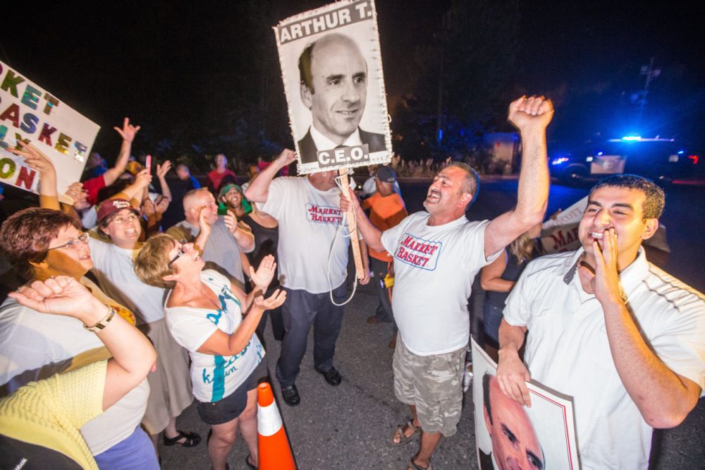 Protesters celebrate outside Market Basket headquarters in Tewksbury after the grocery chain reached a deal to return control back to Arthur T. Demoulas. (Aram Boghosian for WBUR)
