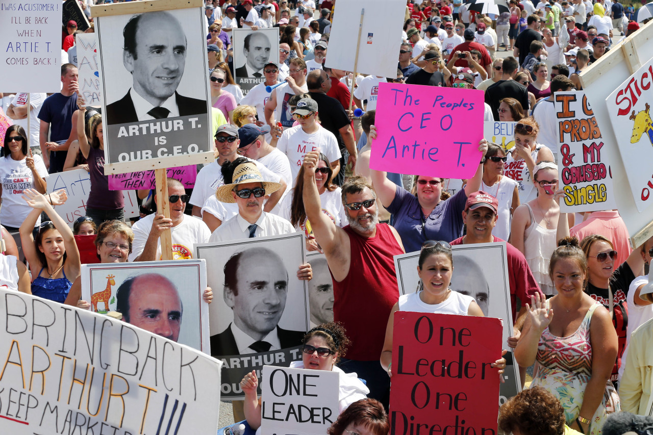 Protesters hold signs during a rally at Market Basket in Tewksbury, Mass., Tuesday, Aug. 5, 2014. Thousands of Market Basket supermarket employees and their supporters are calling for the reinstatement of their fired CEO, even as the company began a three-day job fair to replace employees who have refused to work during a revolt that is costing the supermarket chain millions. (AP)