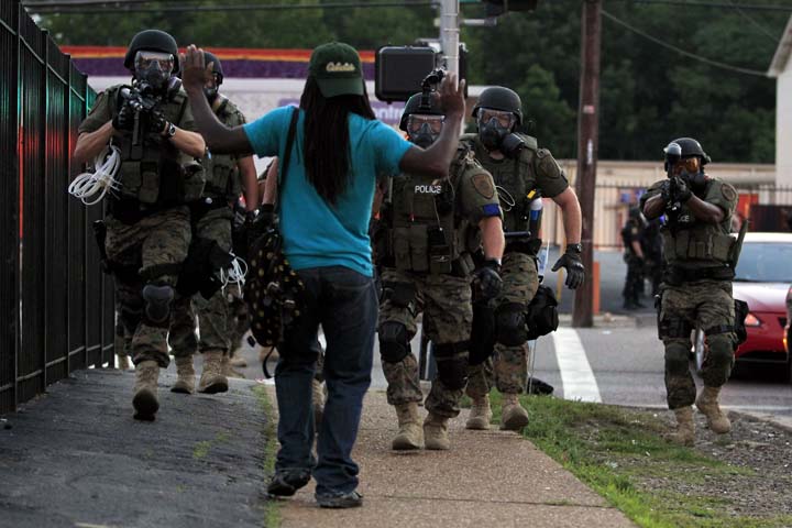 Police wearing riot gear walk toward a man with his hands raised Monday, Aug. 11, 2014, in Ferguson, Mo.  (AP)