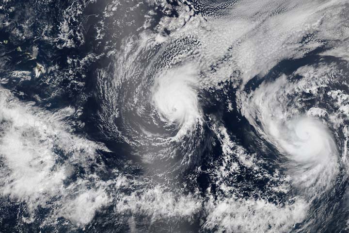 This Aug. 5, 2014 satellite image provided by NASA shows two tropical Pacific Ocean hurricanes - Iselle at center and Julio at right - bearing down on Hawaii, top left. (AP)