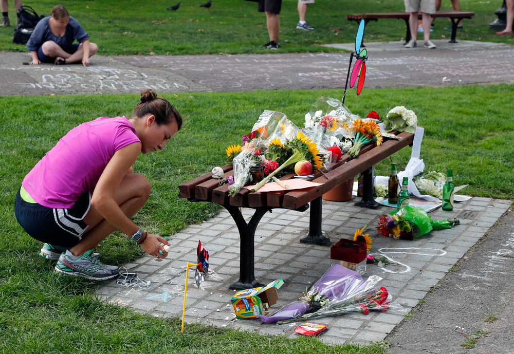 People write chalk messages by a bench at Boston's Public Garden Tuesday, where a small memorial has sprung up at the place where Robin Williams filmed a scene during the film "Good Will Hunting." (Elise Amendola/AP)