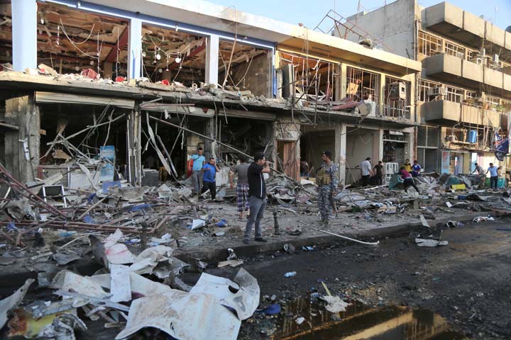 Iraqi policemen and civilians inspect the site of a car bomb attack near a restaurant in the southeastern district of New Baghdad, Iraq, Wednesday, Aug. 13, 2014. (AP)