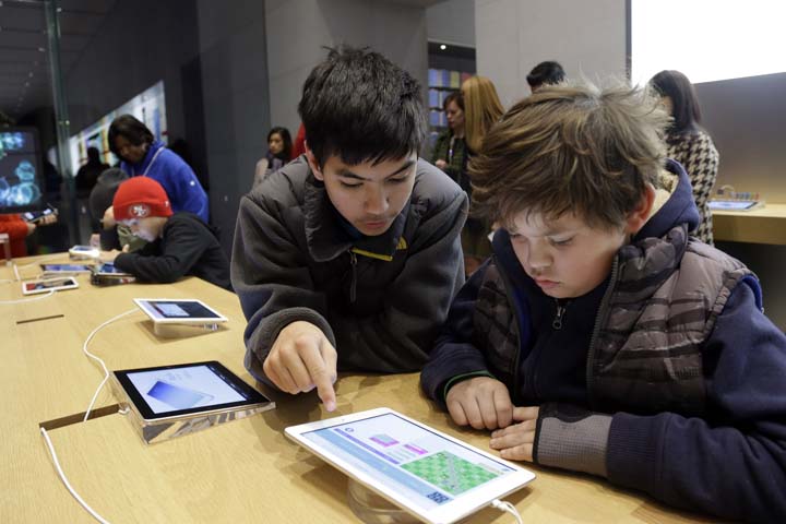 Matthew Triska, 13, center, helps Alex Fester, 10, to build code using an iPad at a youth workshop at the Apple store on Wednesday, Dec. 11, 2013, in Stanford, Calif.  (AP)