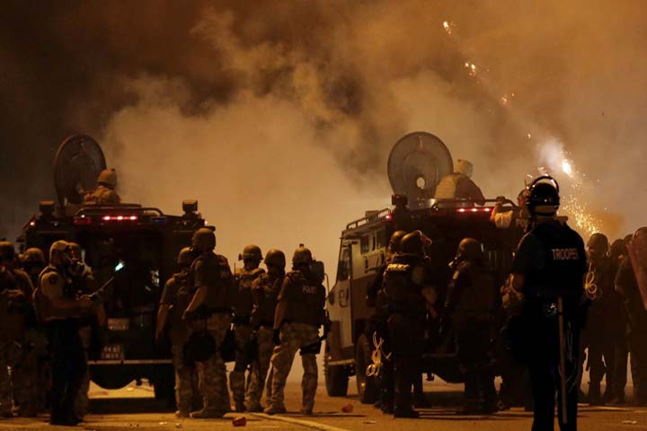 Police wait to advance after tear gas was used to disperse a crowd Sunday, Aug. 17, 2014, during a protest for Michael Brown, who was killed by a police officer last Saturday in Ferguson, Mo. (AP)