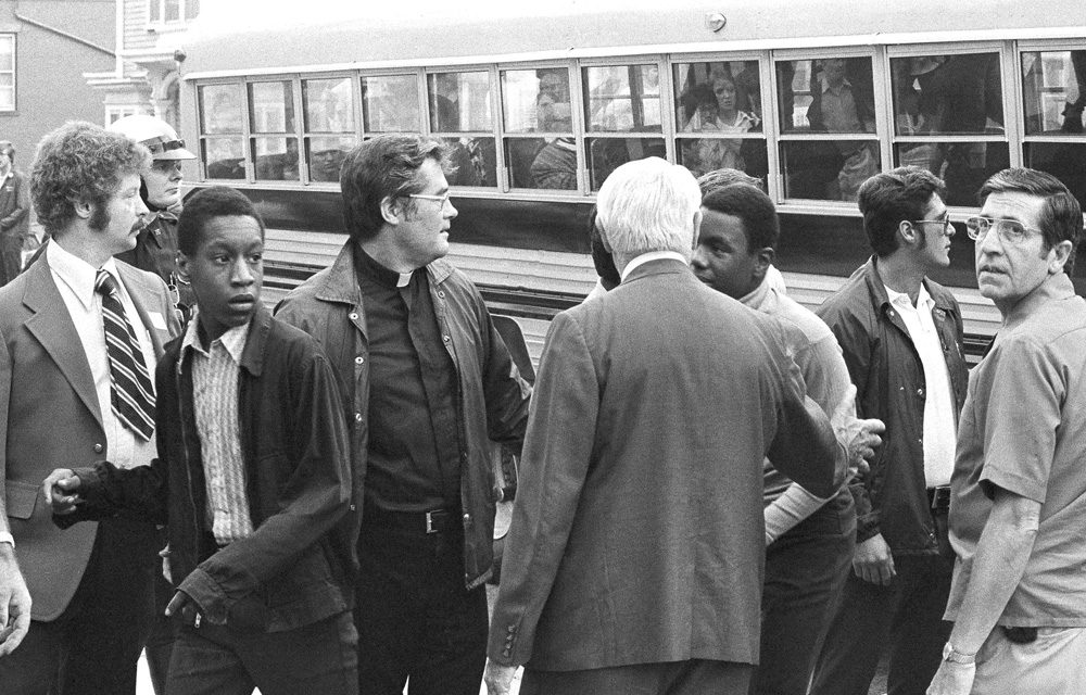 Two black students walk through a line of officials as they leave a bus to attend predominantly white South Boston High School on Sept. 12, 1974, the first day of a court-ordered busing. 