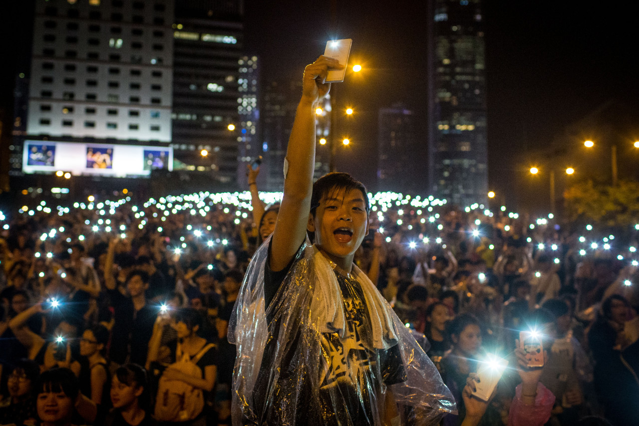 Protesters sing songs and wave their cell phones in the air outside the Hong Kong Government Complex on September 30, 2014. Thousands of pro democracy supporters continue to occupy the streets surrounding Hong Kong's Financial district despite authorities demanding they withdraw. (Chris McGrath/Getty Images)