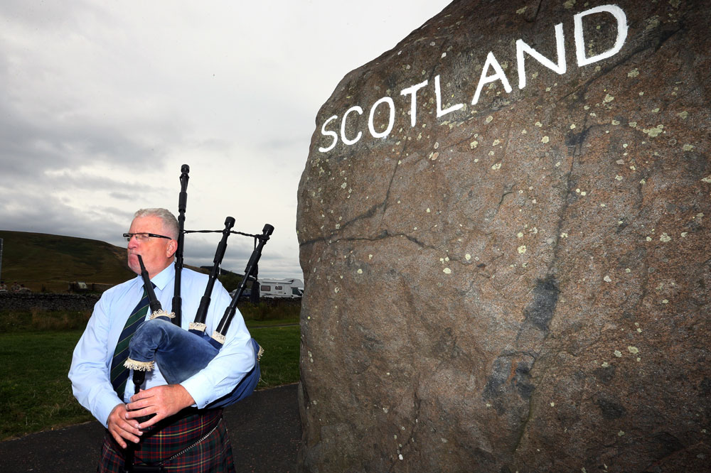 Allan Smith plays his bagpipes for the passing tourists that stop at the Scotland-England border at Carter Bar, Scotland, Monday, Sept. 8, 2014.   (AP/Scott Heppell)