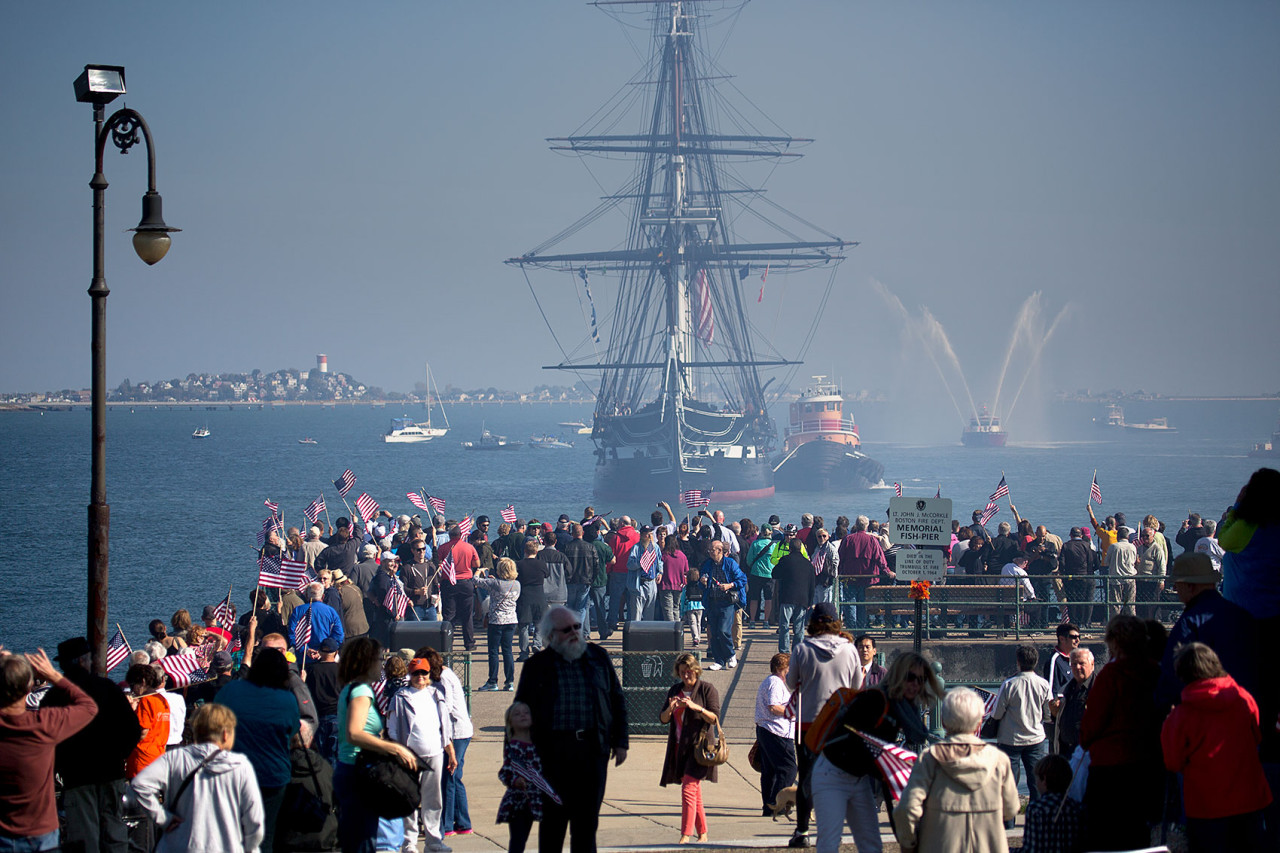 The USS Constitution faces a crowd on the Fish Pier at Castle Island after a gun salute on what is the final voyage around Boston Harbor before the ship goes into drydock for restoration. (Jesse Costa/WBUR)