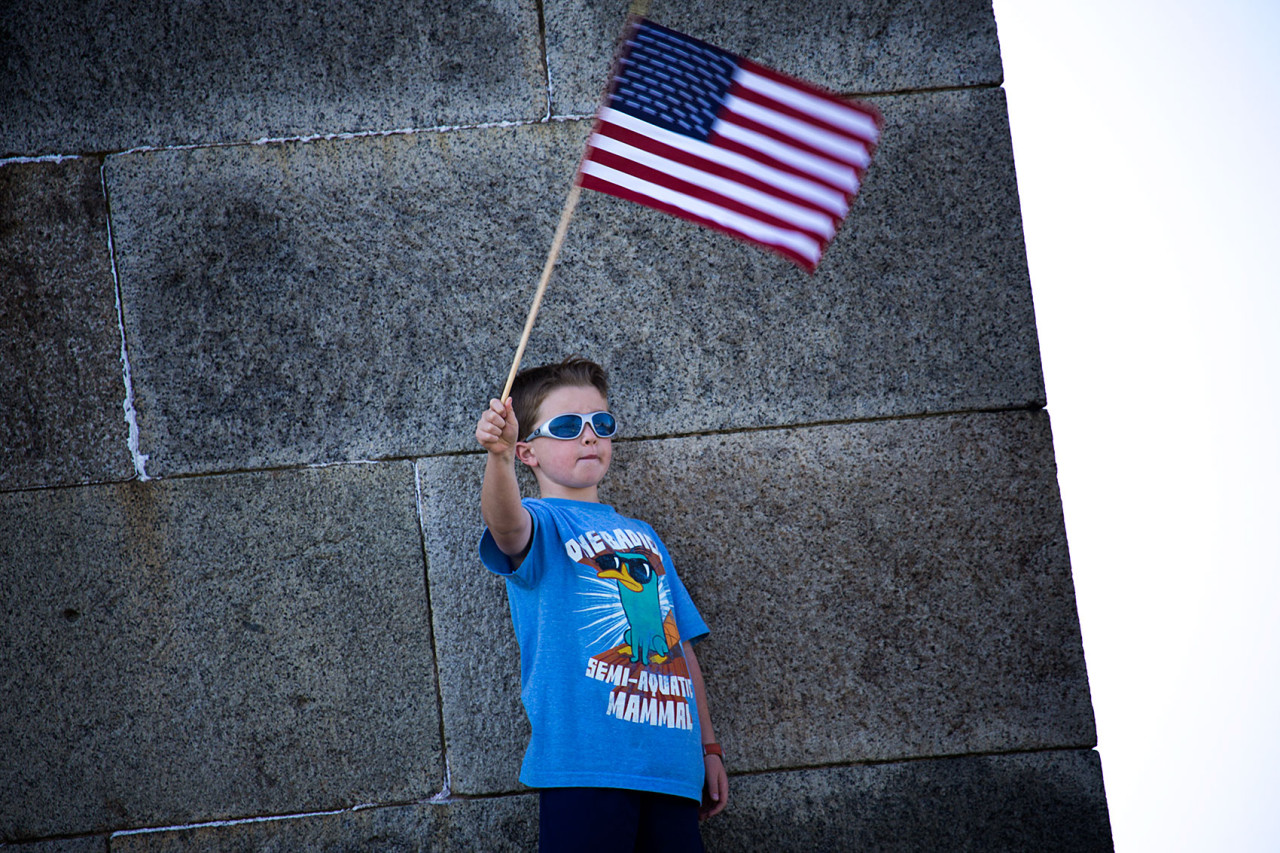 A boy waves a flag by the wall of Fort Independence. (Jesse Costa/WBUR)