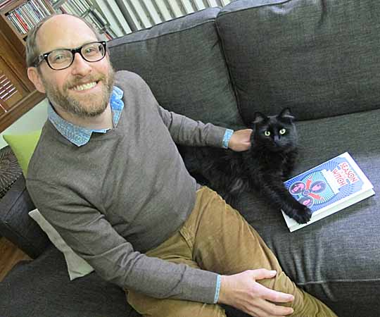 Cambridge author Peter Bebergal sits with his cat and his latest book. (Andrea Shea/WBUR)