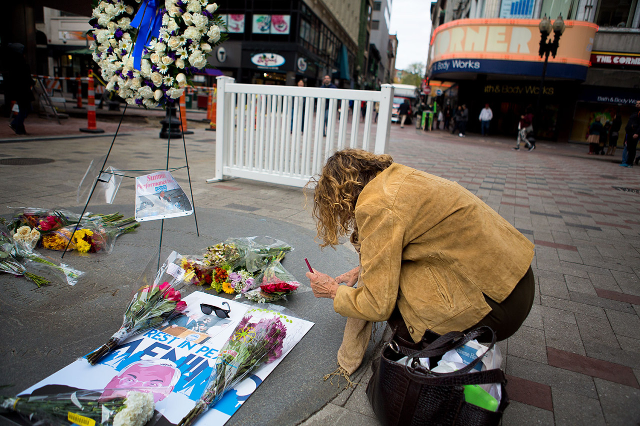 A woman leaves a message on the poster left in the Memorial at Downtown Crossing. (Jesse Costa/WBUR)