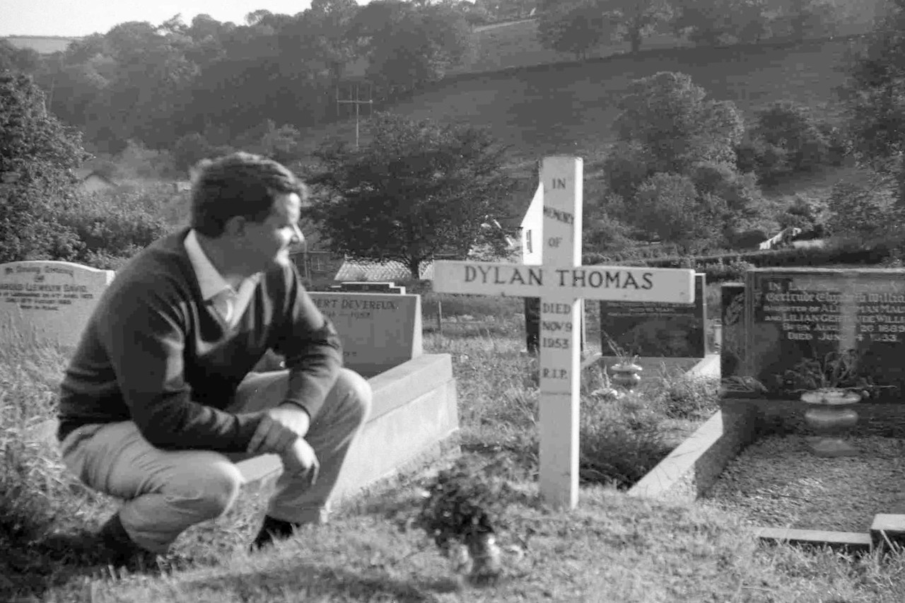 A visitor looks at the simple wooden cross that marks the grave of Welsh poet and playwright Dylan Thomas, in Laugharne, Wales, Sept. 17, 1963. (AP)