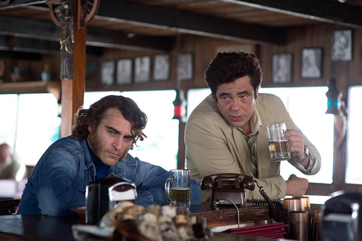 Doc Sportello (Joaquin Phoenix) and Sauncho Smilax (Beninico del Toro) share a drink in a scene from the upcoming Paul Thomas Anderson film, "Inherent Vice," an adaptation of the Thomas Pynchon novel of the same name. (Courtesy Warner Bros. Entertainment)