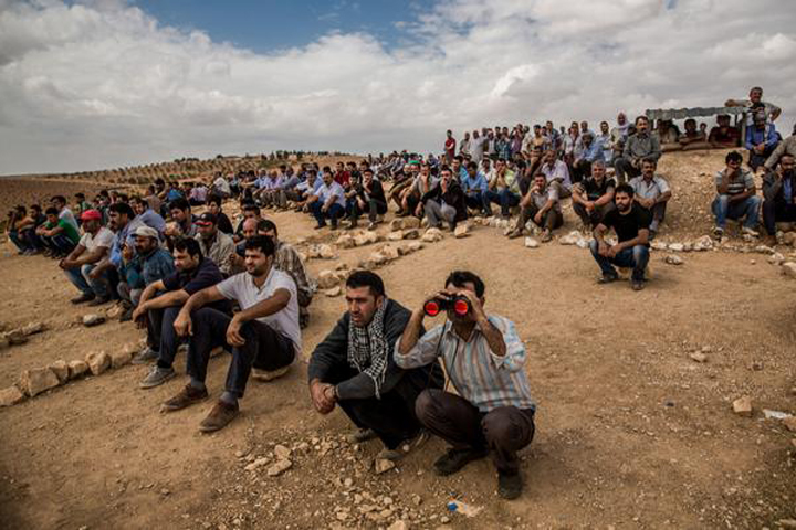 Kurds in Turkey look over the border with Syria toward the embattled town of Kobani. (David Takaki / Twitter)