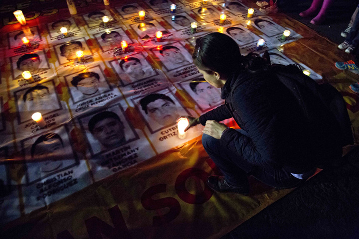 A woman places a candle on photos of the missing students during a protest against the disappearance of 43 students from the Isidro Burgos rural teachers college, in Mexico City, Wednesday, Oct. 22, 2014. Tens of thousands marched in Mexico City's main avenue demanding the return of the missing students. (AP)
