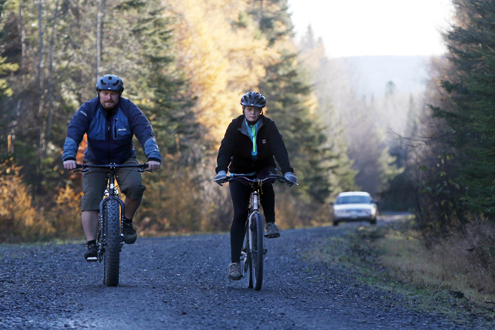 Nurse Kaci Hickox, right, and her boyfriend, Ted Wilbur are followed by a Maine State Trooper as they ride bikes on a trail near her home in Fort Kent, Maine, Thursday, Oct. 30, 2014.  (AP)