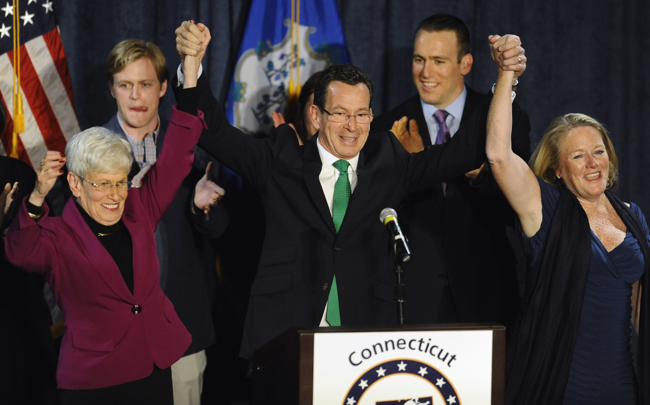 Incumbent Democratic Gov. Dannel P. Malloy, raises his arms over his head with Lt. Gov. Nancy Wyman, left, and his wife Cathy Malloy, right, after speaking to supporters at his party&#039;s rally, Wednesday. (Jessica Hill/AP)