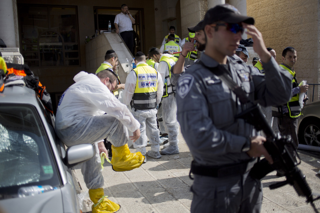 An Israeli police officer and Israeli rescue workers work at the scene. (Ariel Schalit/AP)