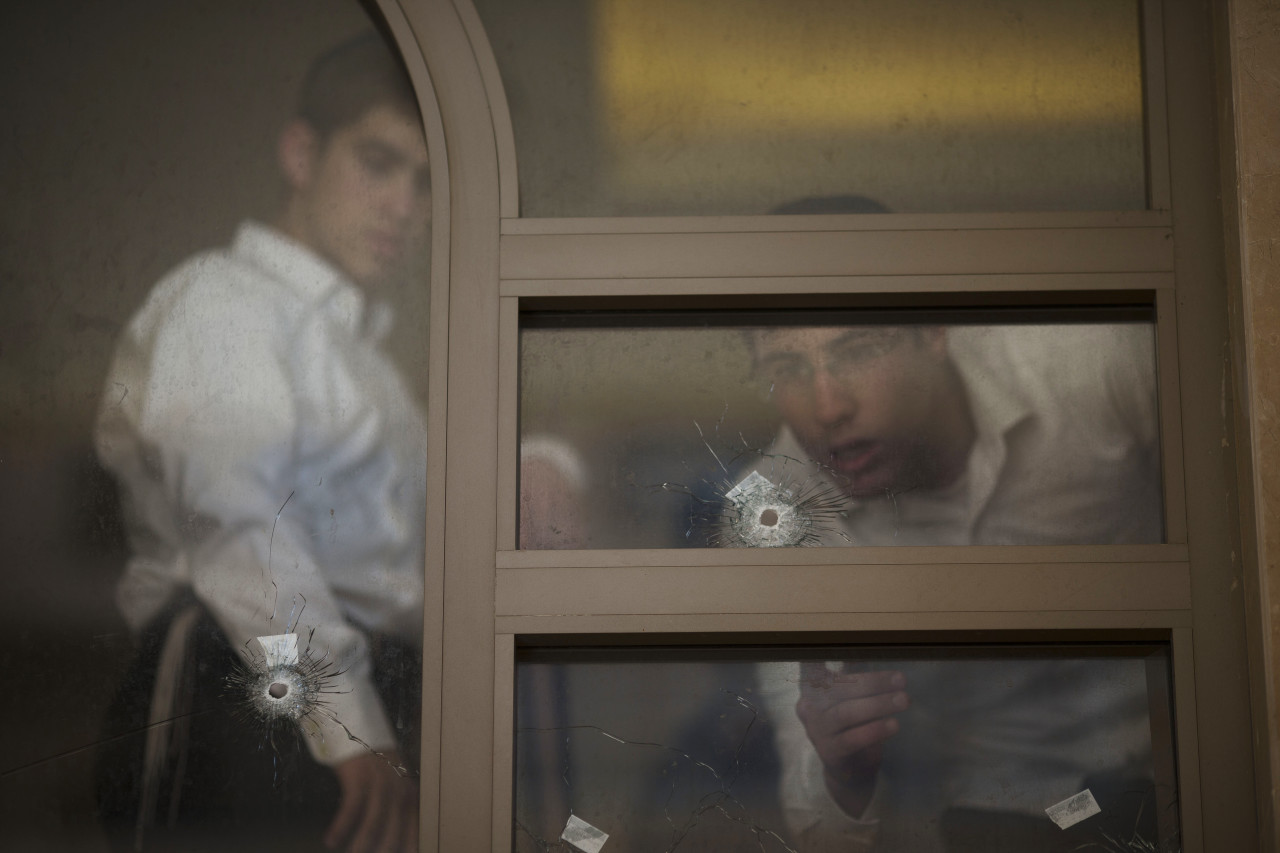 Two youths look at bullet holes and forensic evidence inside a synagogue after an attack in Jerusalem. (Ariel Schalit/AP)