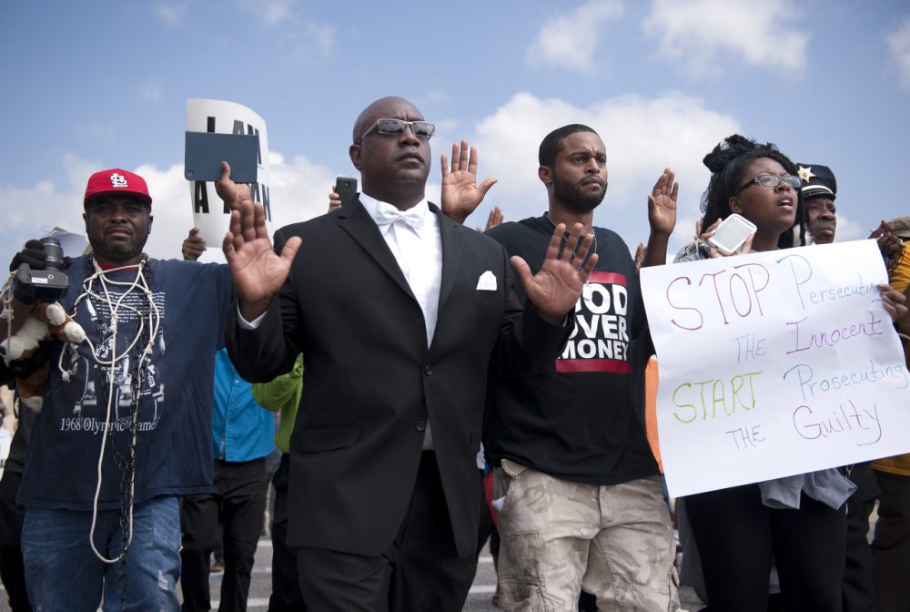 Protestors march along Florissant Road in downtown Ferguson, Mo. Monday, Aug. 11, 2014. The group marched along the closed street, rallying in front of the town's police headquarters to protest the shooting of 18-year-old Michael Brown by Ferguson police officers on Saturday night. (Sid Hastings/AP)