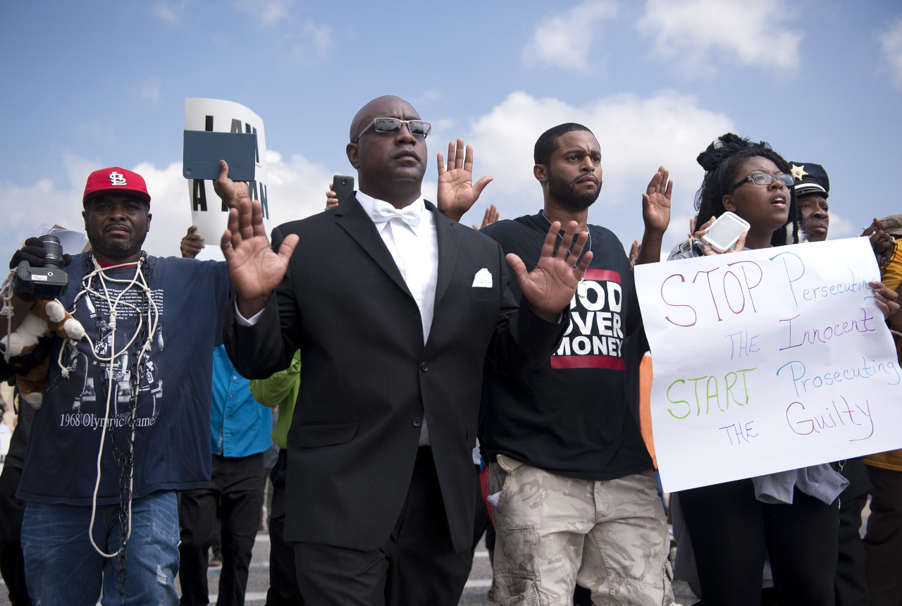 Protestors march along Florissant Road in downtown Ferguson, Mo. Monday, Aug. 11, 2014. The group marched along the closed street, rallying in front of the town's police headquarters to protest the shooting of 18-year-old Michael Brown by Ferguson police officers on Saturday night. (Sid Hastings/AP)