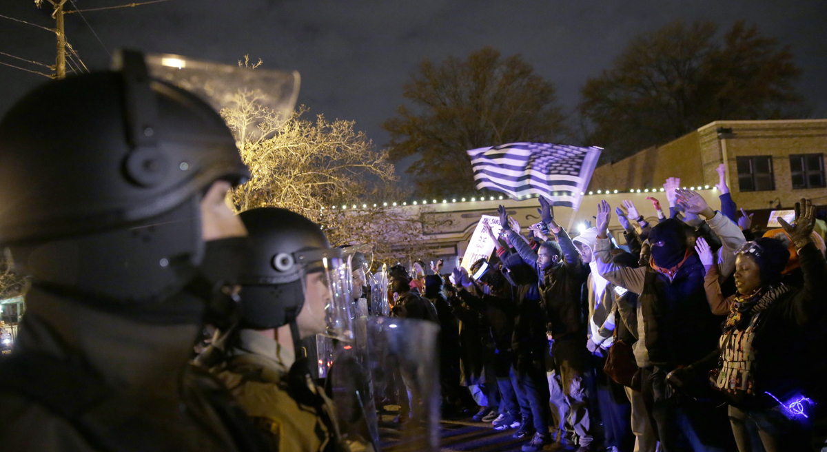 Carol Rose: "If you don’t think what happened in Ferguson can happen here, think again." Pictured: Police officers guard as protesters react to the announcement of the grand jury decision, Monday, Nov. 24, 2014, in Ferguson, Mo. A grand jury has decided not to indict Ferguson police officer Darren Wilson in the shooting death of 18-year-old Michael Brown. (David Goldman/AP)