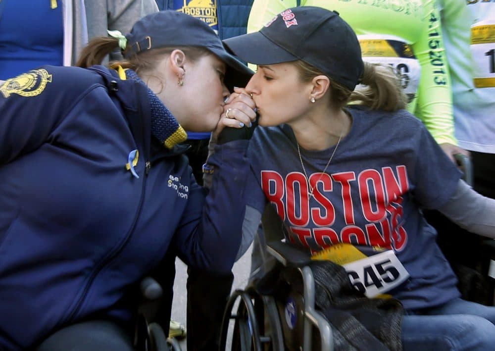 Boston Marathon bombing survivors Erika Brannock, left, and Rebekah Gregory embrace in their wheelchairs as they head to the finish line of the Boston Marathon Tribute Run on April 19, 2014. (Elise Amendola/AP)