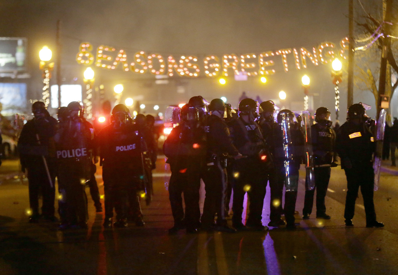 Police gather on the street as protesters react after the announcement of the grand jury decision. (Charlie Riedel/AP)