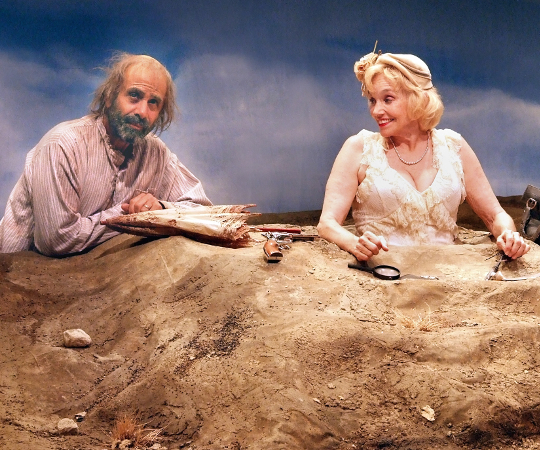 This reexamination of the Samuel Beckett's "Happy Days" features Brooke Adams as Winnie, a woman buried up to her bosom in a mound of dirt, and her husband Willie, (Tony Shalhoub), lurking somewhere behind her. (Courtesy Ed Krieger)